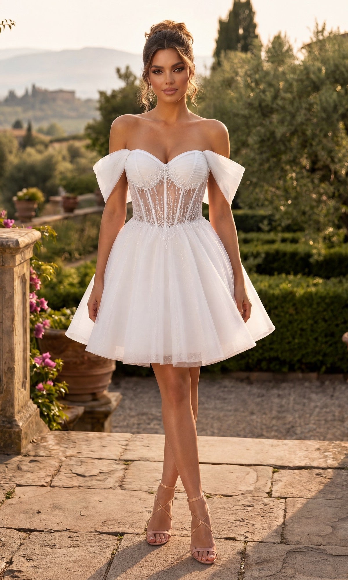 Wearing the Chicas C363 Short Homecoming Dress in Off White, a woman stands outdoors on a stone path in a garden. The elegant A-line design features a short, off-the-shoulder neckline with a sheer corset bodice and tulle skirt.